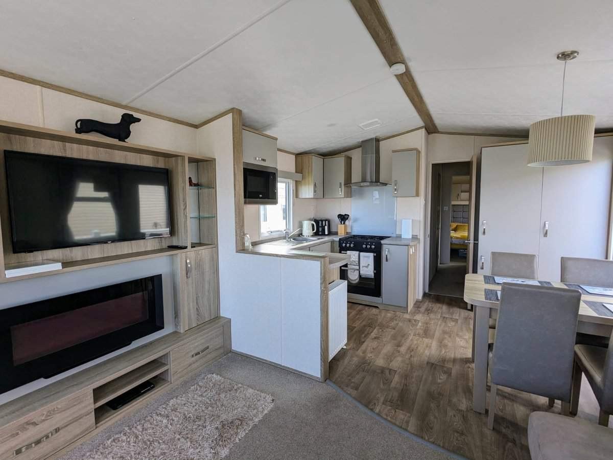 Modern pet-friendly holiday caravan interior with open-plan kitchen, living area, and wooden flooring throughout